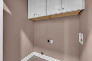 Washroom featuring washer hookup, cabinet space, electric dryer hookup, and baseboards