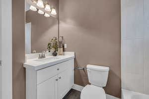 Bathroom with walk in shower, vanity, toilet, and baseboards