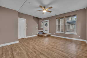 Unfurnished living room with a ceiling fan, baseboards, visible vents, and light wood finished floors