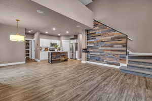 Living room featuring wooden walls, baseboards, stairway, light wood-style floors, and recessed lighting