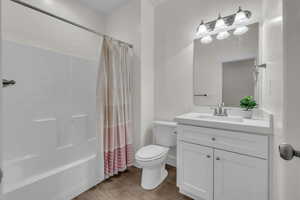 Bathroom with shower / bath combo, vanity, and toilet