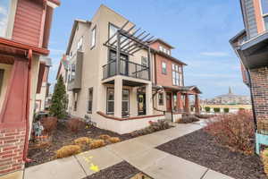 View of side of property featuring a porch, a balcony, and stucco siding