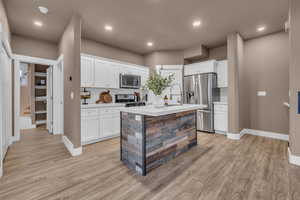 Kitchen with light countertops, appliances with stainless steel finishes, white cabinets, and light wood-style floors