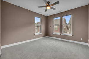 Empty room with ceiling fan, carpet flooring, visible vents, and baseboards