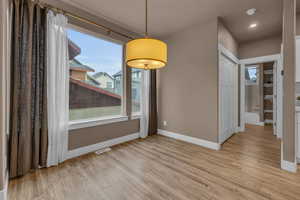 Unfurnished dining area featuring light wood-type flooring, visible vents, and baseboards