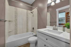 Bathroom featuring vanity, bathing tub / shower combination, toilet, and wood finished floors