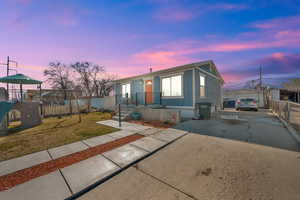 View of front of home featuring a playground, a yard, fence, an outdoor structure, and driveway