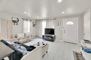 Living room featuring marble finish floor, baseboards, a textured ceiling, and recessed lighting