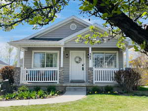 View of front of home with a porch, a front yard, and stone siding
