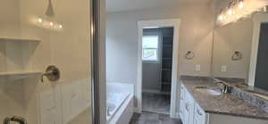 Bathroom with a shower stall, baseboards, a garden tub, and vanity