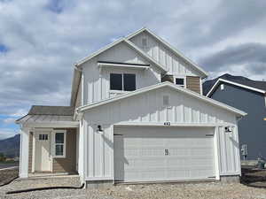 View of front of home featuring driveway, an attached garage, a mountain view, and board and batten siding