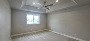 Empty room featuring recessed lighting, baseboards, ceiling fan, a raised ceiling, and light colored carpet