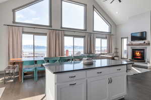 Kitchen with dark wood finished floors, a glass covered fireplace, white cabinets, a mountain view, and high vaulted ceiling