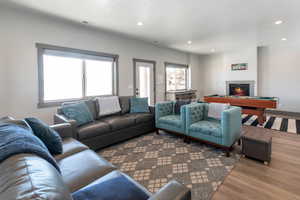 Living room featuring a glass covered fireplace, visible vents, recessed lighting, and wood finished floors