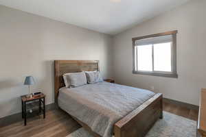 Bedroom featuring vaulted ceiling, wood finished floors, and baseboards