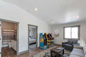 Living room featuring baseboards, visible vents, dark wood finished floors, vaulted ceiling, and recessed lighting