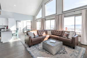 Living room with high vaulted ceiling, recessed lighting, plenty of natural light, and wood finished floors