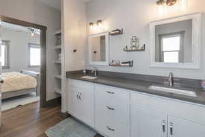 Full bathroom featuring ceiling fan, double vanity, wood finished floors, and a sink