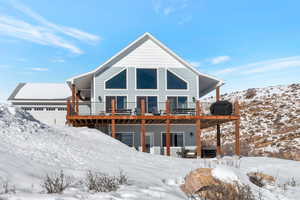 Snow covered rear of property featuring a deck