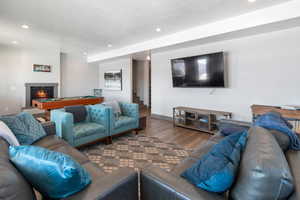 Living area featuring a textured ceiling, recessed lighting, wood finished floors, stairway, and a glass covered fireplace