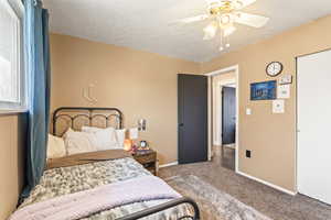 Carpeted bedroom featuring ceiling fan, baseboards, and a textured ceiling