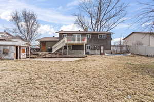 Rear view of property featuring stairs, fence, a lawn, and a wooden deck