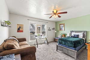 Carpeted bedroom with ceiling fan and a textured ceiling