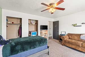 Carpeted bedroom featuring a closet, ceiling fan, and a textured ceiling