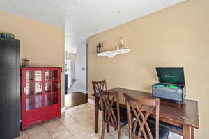 Dining space featuring light tile patterned floors, baseboards, and a textured ceiling