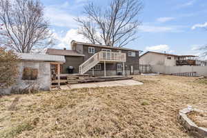 Rear view of property with a lawn, a chimney, stairway, fence, and a deck