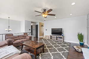 Living room featuring a textured ceiling, baseboards, wood finished floors, and recessed lighting