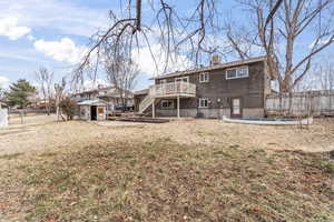 Back of house with an outbuilding, a fenced backyard, a storage unit, and stairs