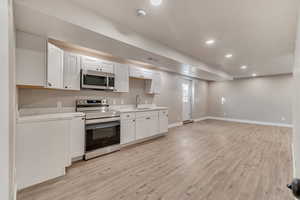 Kitchen with stainless steel appliances, recessed lighting, light wood-style floors, a sink, and baseboards