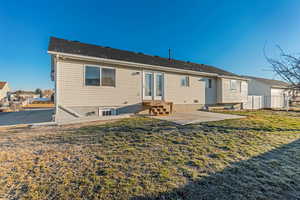 Rear view of property with a yard, entry steps, fence, and a patio