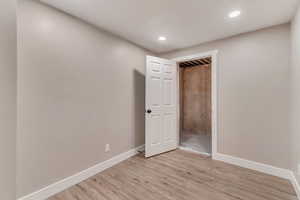 Empty room with light wood finished floors, recessed lighting, and baseboards