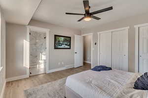 Bedroom with baseboards, visible vents, ensuite bath, wood finished floors, and two closets