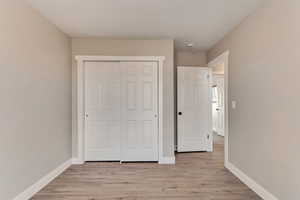 Unfurnished bedroom featuring light wood-style floors, a closet, and baseboards