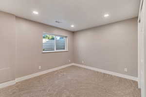 Carpeted spare room with recessed lighting, visible vents, and baseboards