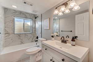 Bathroom featuring toilet, bathtub / shower combination, visible vents, and vanity