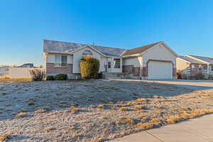 Single story home featuring concrete driveway, brick siding, an attached garage, and fence