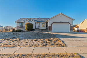 Ranch-style home with concrete driveway, brick siding, fence, and an attached garage