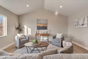 Living room featuring lofted ceiling, baseboards, wood finished floors, and recessed lighting