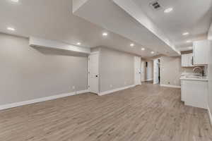 Unfurnished living room featuring baseboards, light wood-type flooring, and recessed lighting