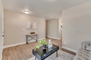 Living area with light wood-style flooring, visible vents, and baseboards