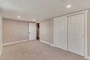 Unfurnished bedroom featuring a textured ceiling, recessed lighting, carpet floors, baseboards, and a closet