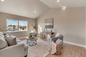 Living room with lofted ceiling, light wood finished floors, and baseboards