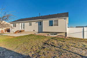 Back of property with entry steps, a patio area, fence, and a lawn