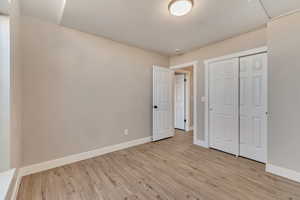 Unfurnished bedroom with baseboards, a closet, and light wood-style floors