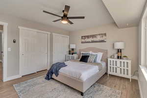 Bedroom with ceiling fan, baseboards, two closets, and wood finished floors