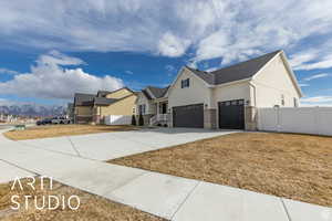 View of property exterior featuring fence, stucco siding, concrete driveway, a garage, and a mountain view